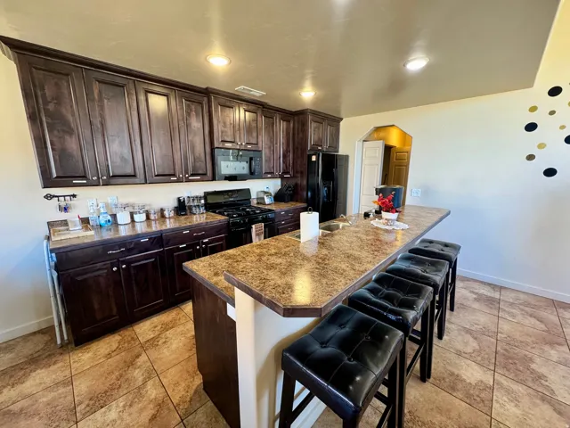 Kitchen featuring dark wood-finish cabinetry, a freestanding range with microwave, a built-in kitchen island, and tiled flooring