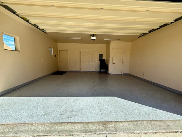 Expansive garage featuring a speckled epoxy floor, multiple entry doors, and built-in overhead lighting