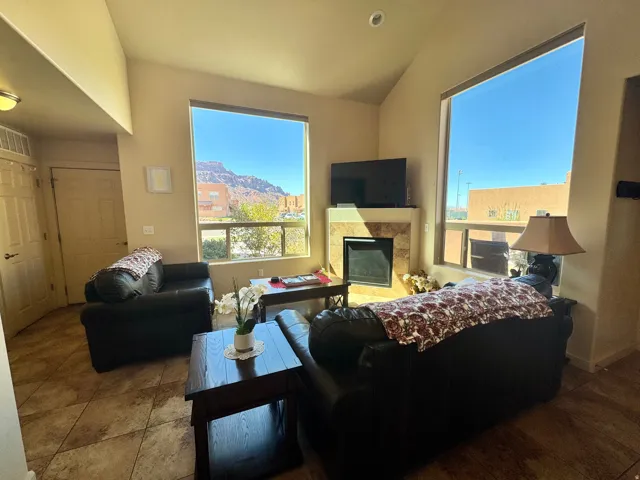 Vaulted ceiling living area featuring large windows, a tiled fireplace with a built-in mantel, and diagonal tile flooring