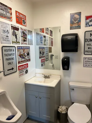 Vanity with a built-in sink and two-door cabinet, wall-mounted mirror, white toilet, and white urinal