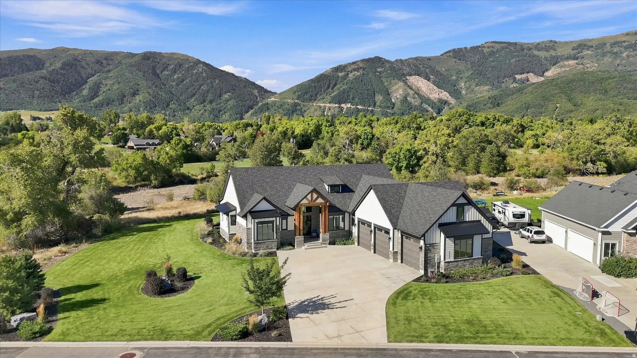 Contemporary residence featuring a paved driveway, attached multi-car garage, and a gabled roofline