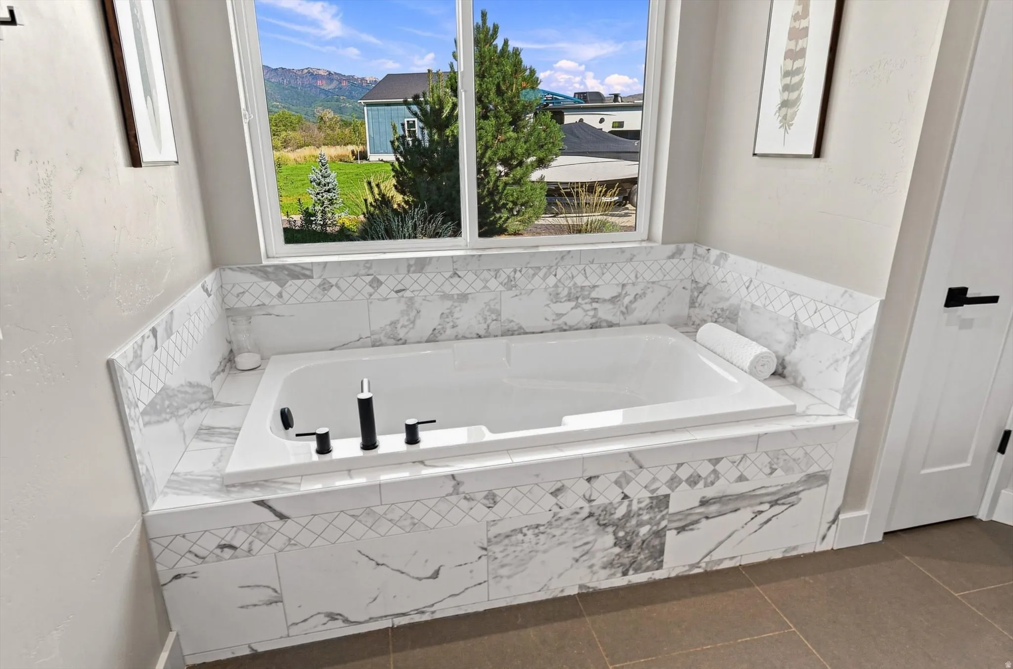 Built-in soaking tub with a surrounding marble-patterned tile deck and wainscoting