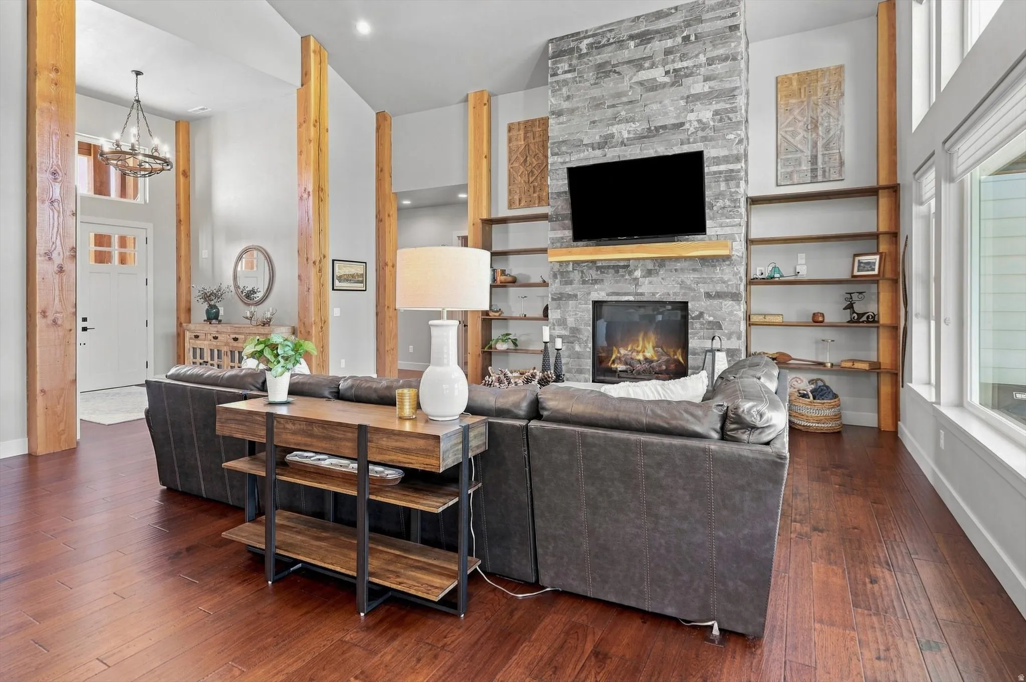 Vaulted ceilings, wood-finish flooring, stone-clad fireplace, built-in shelving, and large windows