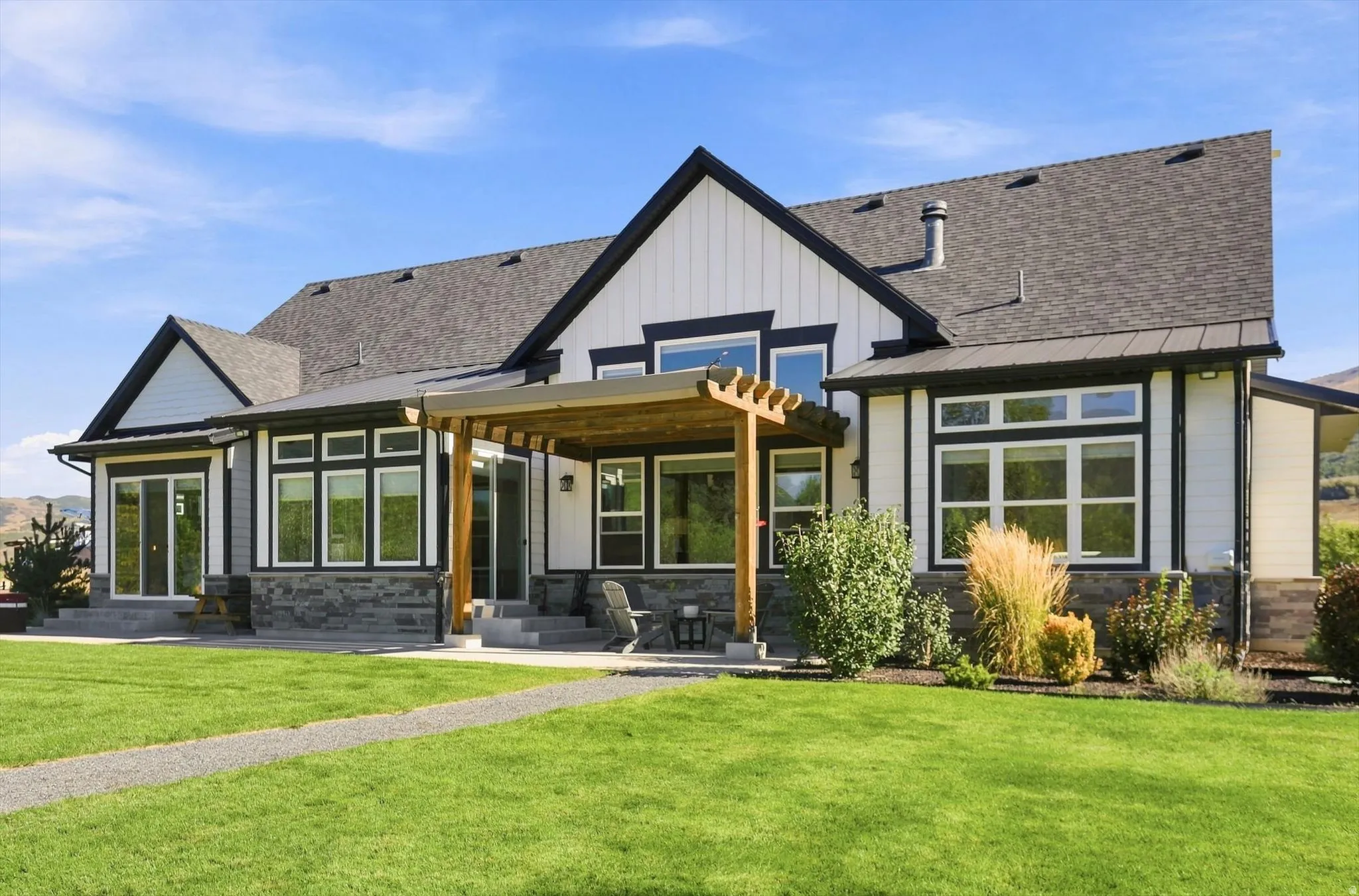 Exterior featuring a pergola, stone accents, and multiple large windows