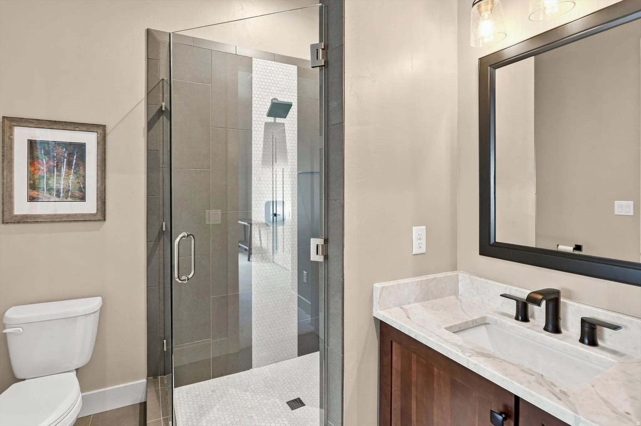Glass-enclosed shower with subway tile surround and hexagonal tile flooring