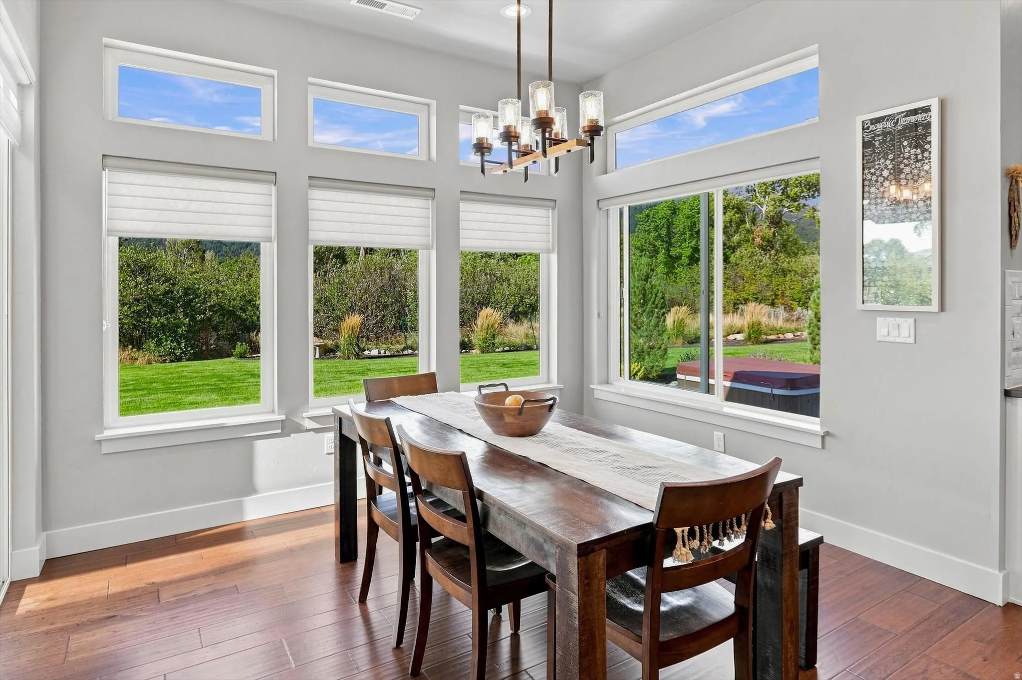 Hardwood-finish flooring, multiple large windows, transom windows, contemporary chandelier, and light-toned wall paint