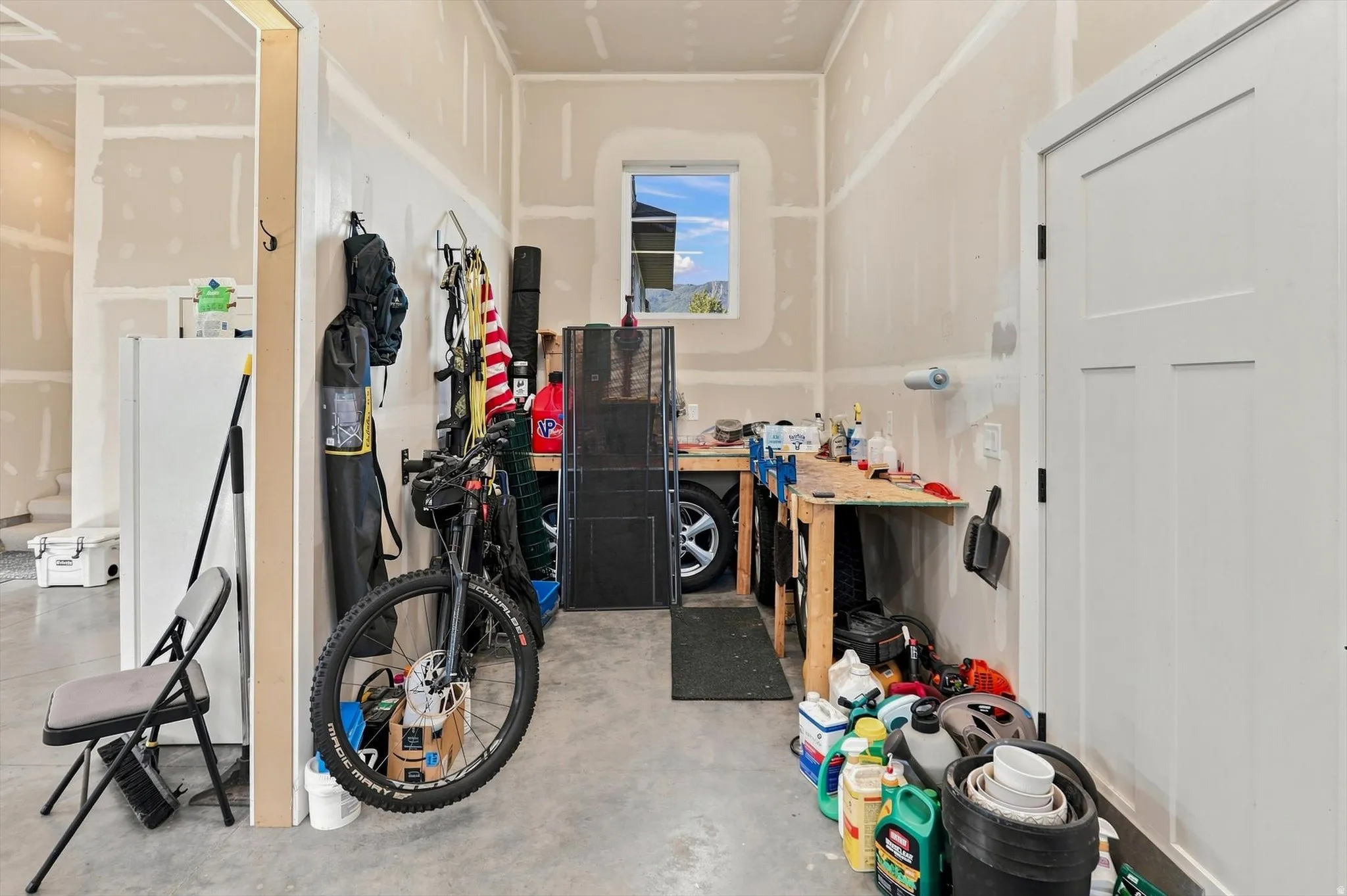 Garage space with a window, concrete flooring, built-in workbench, and a three-panel interior door