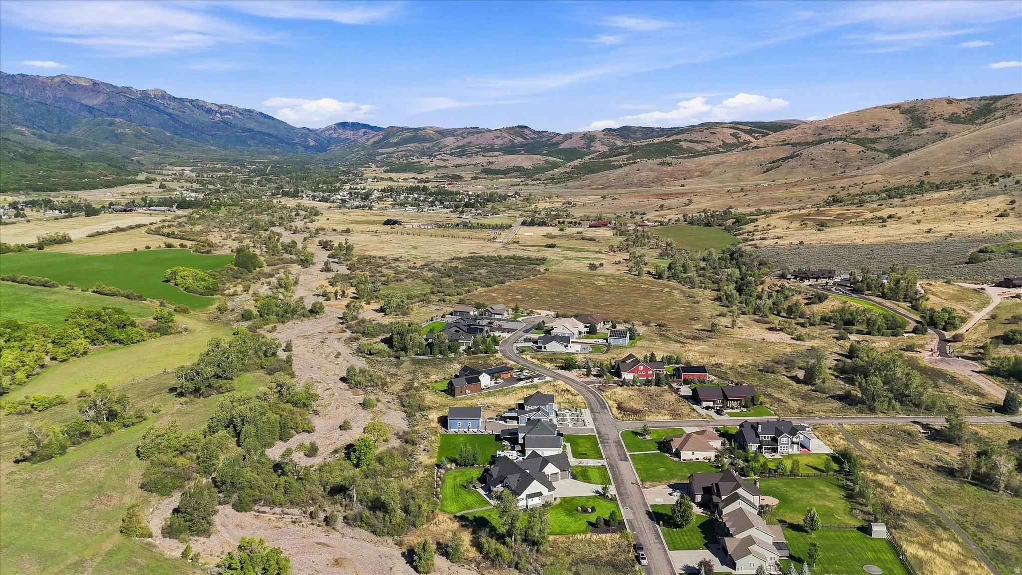 Expansive valley setting with residential development, surrounded by rugged mountains and green fields