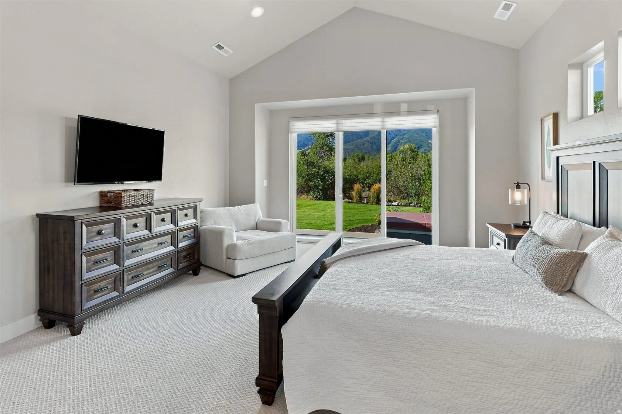 Vaulted ceilings, recessed lighting, carpet flooring, large sliding glass doors, and transom windows