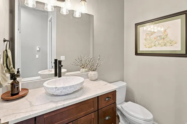 Stone vessel sink with a wall-mounted matte black faucet, set on a light-toned countertop