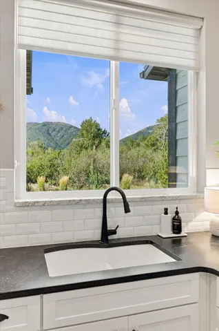 White kitchen cabinets, subway tile backsplash, dark countertop, single-basin sink, and a matte black gooseneck faucet
