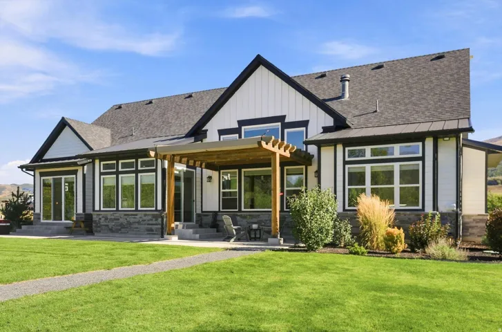Exterior featuring a pergola, stone accents, and multiple large windows