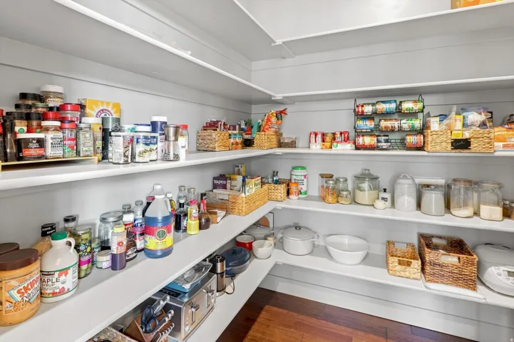 Spacious pantry with extensive shelving and wood-finish flooring