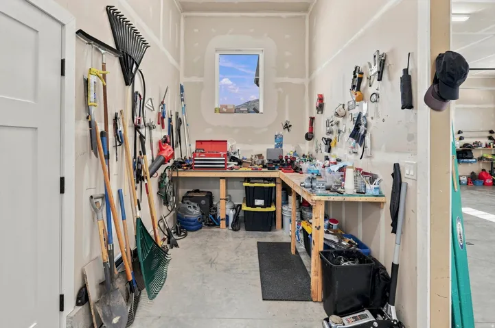 Dedicated workshop area featuring a built-in workbench, wall-mounted tool storage, and a single window