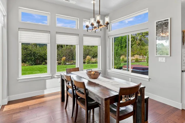 Hardwood-finish flooring, multiple large windows, transom windows, contemporary chandelier, and light-toned wall paint