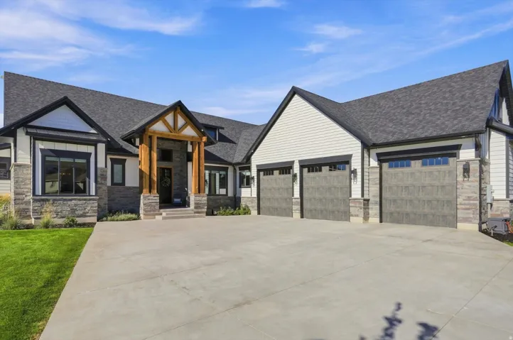 Contemporary exterior with stone accents, an exposed timber entry, and a multi-car garage