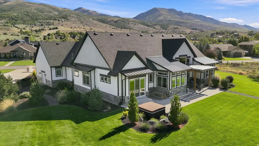 Contemporary home featuring white siding, dark trim, a dark roof, stone accents, and a spacious patio