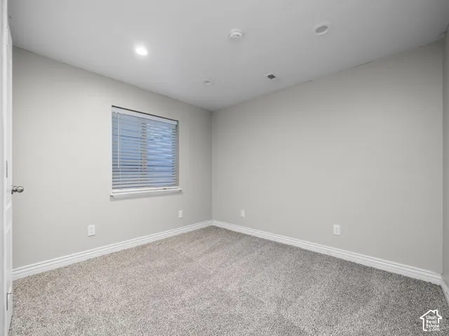 Neutral wall paint, recessed ceiling lighting, textured carpeting, window blinds, and white trim
