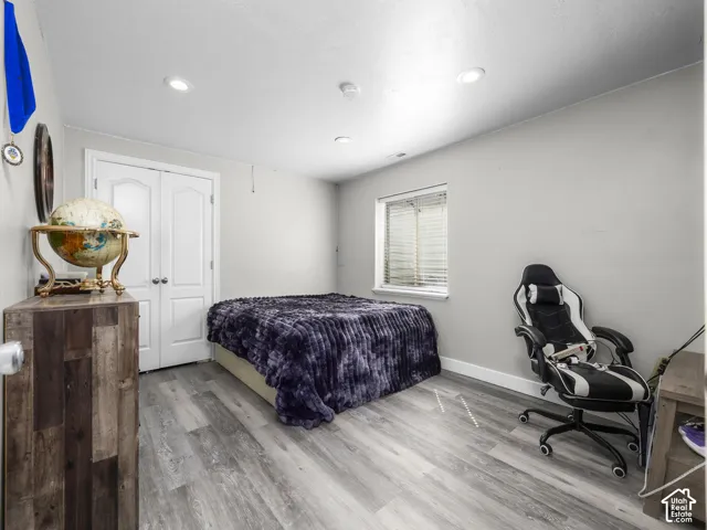 Recessed lighting, wood-finish flooring, white double doors, and a window with blinds