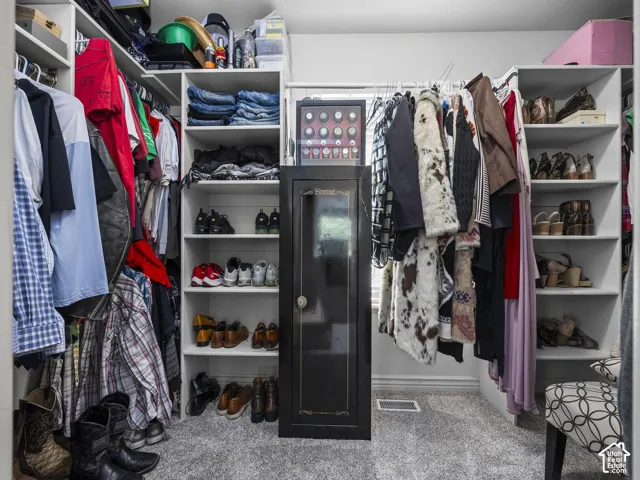 Walk-in closet featuring extensive built-in shelving, multiple hanging rods, and light gray carpeting
