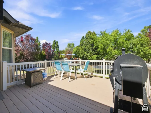 Expansive outdoor deck featuring wood-finish flooring, white railing, and a window with blinds