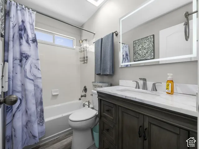 Vanity with integrated sink, wood-finish cabinetry, and stone countertop