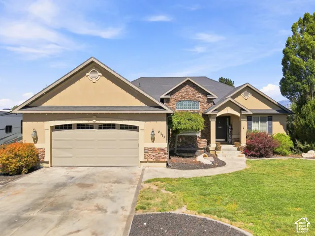 Stucco exterior featuring stone accents, an integrated two-car garage, and a covered entry