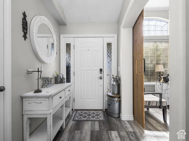 Entryway featuring wood-finish flooring, a paneled entry door with decorative sidelights, and a sliding wood panel door