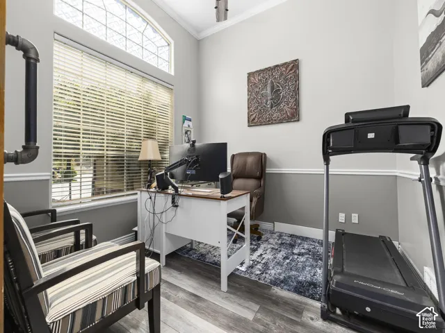 Room featuring wood-finish flooring, a decorative arched window, crown molding, and two-tone wall paint