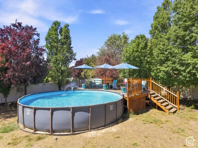 Above-ground pool featuring a water fountain and surrounding wooden deck with stairs