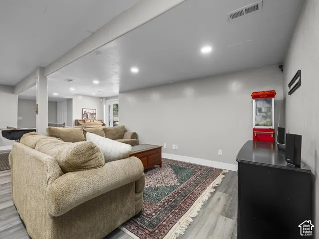 Recessed lighting illuminates the open-concept living space with light-toned walls and wood-finish flooring