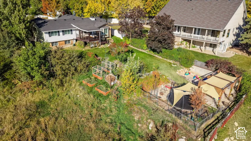Expansive outdoor space featuring a fenced play area with shade sails, raised garden beds, and mature trees