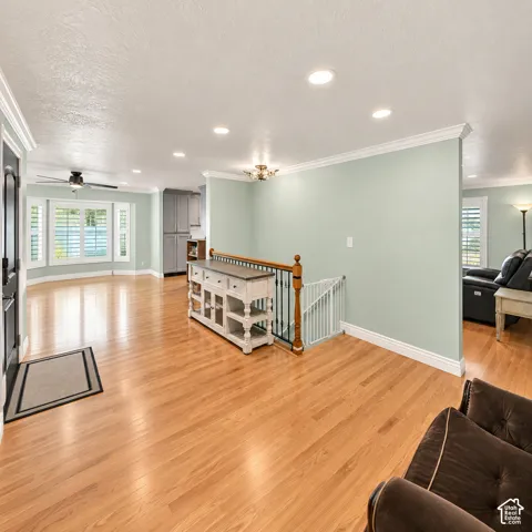 Hardwood flooring throughout, recessed lighting, crown molding, bay window with plantation shutters, and a stairwell with wrought iron balusters