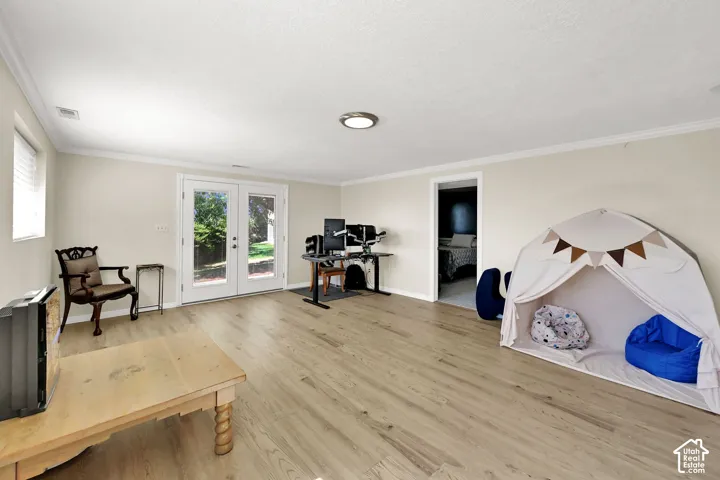 Light wood-finish flooring, white double French doors, recessed lighting, and crown molding