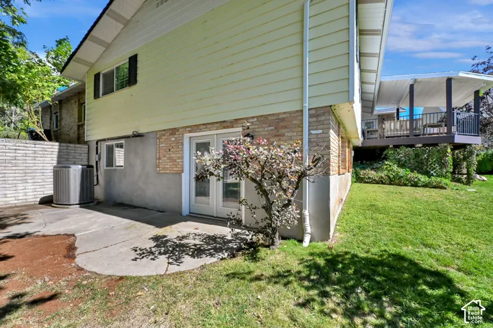 Walk-out basement access with french doors, concrete patio, and a covered deck with railing