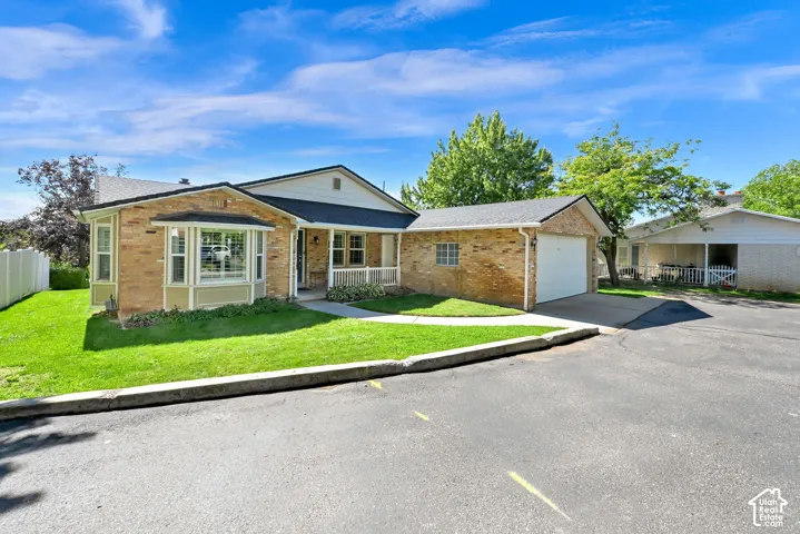 Brick exterior with a prominent bay window, attached garage, covered front porch, and manicured lawn
