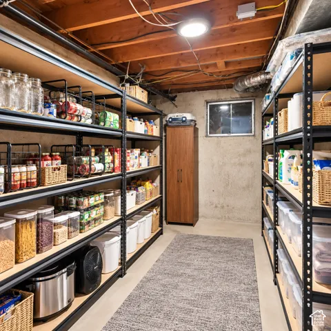 Expansive storage area featuring exposed wood ceiling joists, concrete foundation walls, and a small window