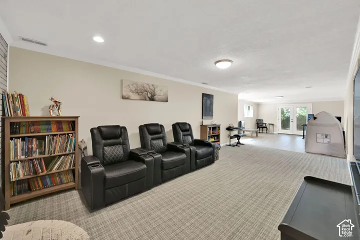 Spacious entertainment area with recessed lighting, crown molding, and direct outdoor access via French doors