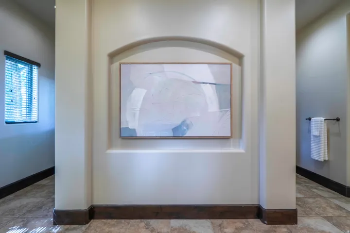 Recessed arched wall niche, neutral wall tones, decorative window with blinds, dark wood-finish trim, and tiled flooring