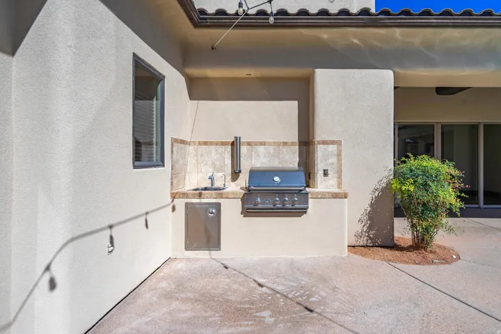 Outdoor built-in grill station featuring a counter, sink, and tiled backsplash