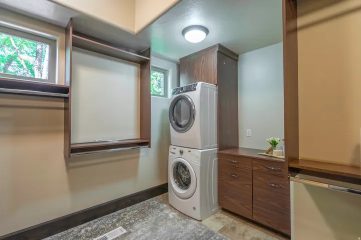 Built-in shelving with clothing rods, upper cabinetry, lower cabinetry with drawers,  washer and dryer, and a ceiling-mounted light fixture