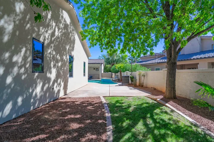 Stucco exterior with dark-framed windows, concrete patio, lawn area, and gravel landscaping