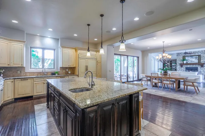 Spacious kitchen featuring a large island with an undermount sink, pendant lighting, built-in appliances, and light-toned cabinetry