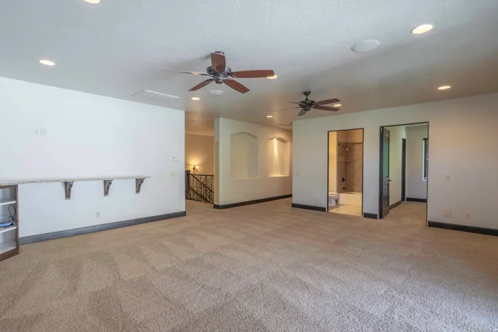 Spacious carpeted room featuring recessed lighting, dual ceiling fans, and built-in shelving