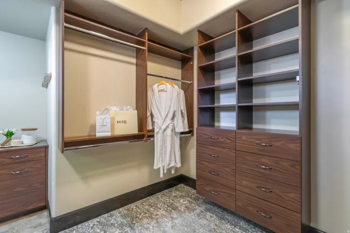 Custom closet system featuring rich wood-finish cabinetry, extensive shelving, and multiple hanging rods for organization