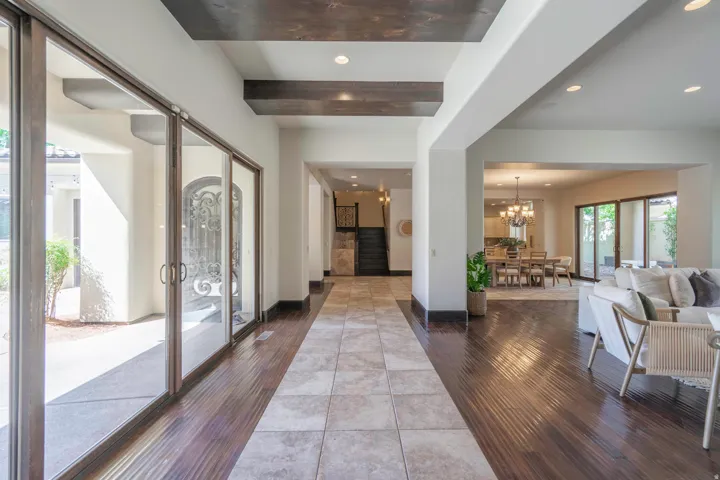 Expansive entry featuring a tray ceiling with wood-finish accents, hardwood flooring, large format tile, and large glass doors