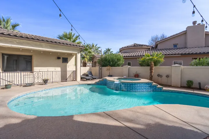 Swimming pool with an integrated spa, surrounded by concrete decking and a stucco privacy wall