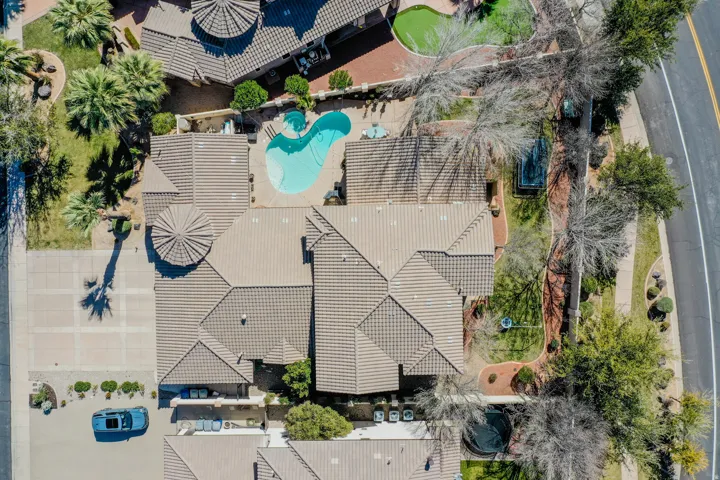 Extensive tile roofing with varied rooflines, private swimming pool, mature palm trees, manicured lawn areas, and paved driveway