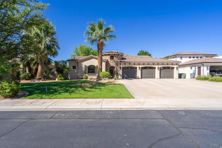 Stucco exterior with stone accents, barrel tile roof, three-car garage, and a concrete driveway