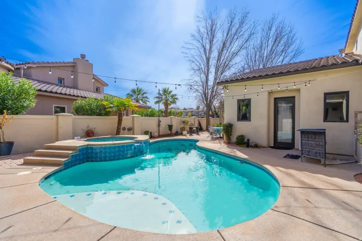 Backyard oasis featuring a swimming pool with integrated spa and tiled accents